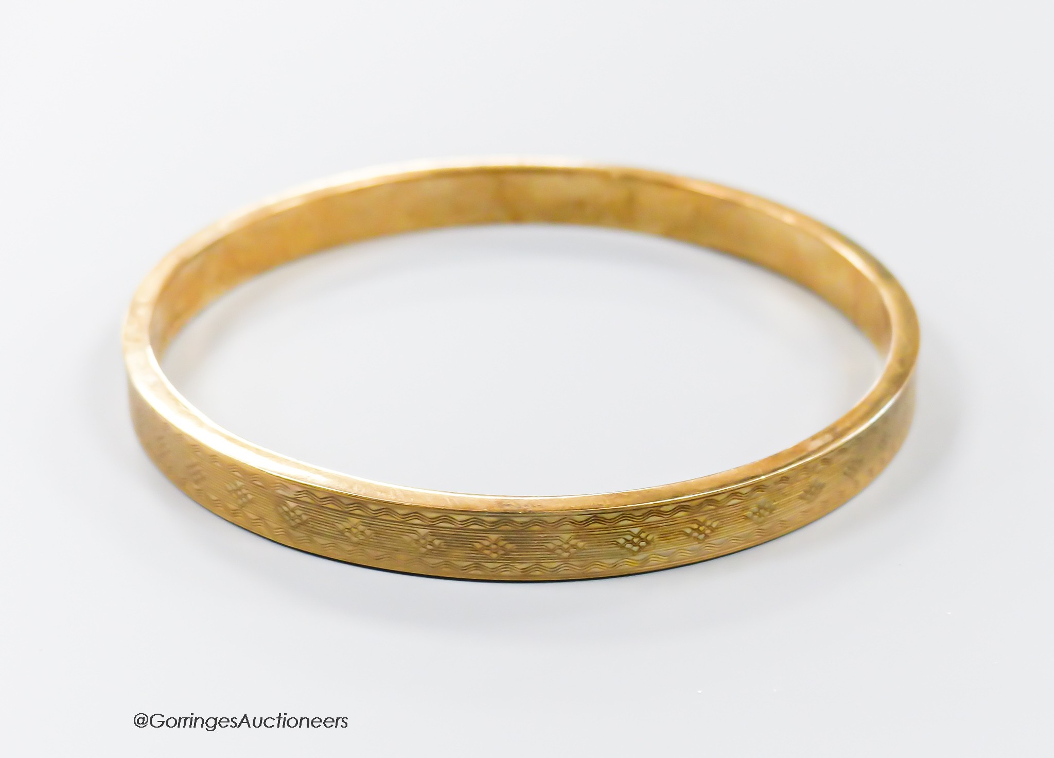 A 1920's engine turned 9ct gold bangle, interior diameter 76mm, 11.9 grams.